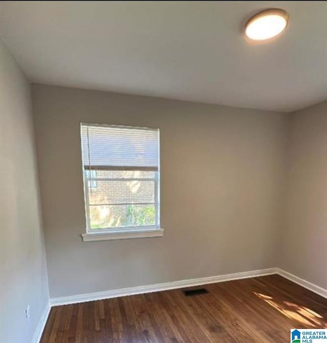 spare room with dark wood-style floors and baseboards