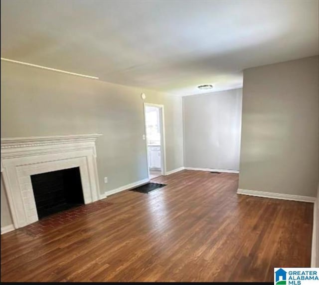 unfurnished living room featuring baseboards, a fireplace, and wood finished floors