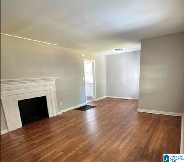 unfurnished living room featuring a fireplace, baseboards, and wood finished floors