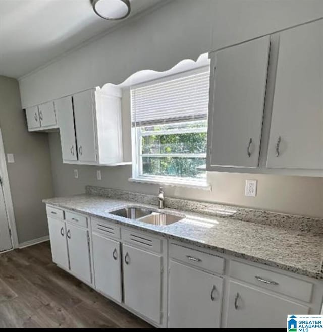 kitchen with a sink, white cabinets, dark wood-style floors, and light stone countertops