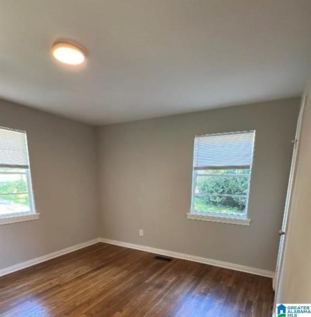 empty room featuring dark wood-style floors and baseboards