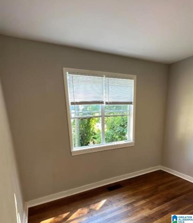 spare room with dark wood-style flooring and baseboards