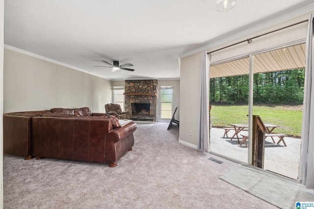 carpeted living room featuring ornamental molding, a ceiling fan, a stone fireplace, and visible vents