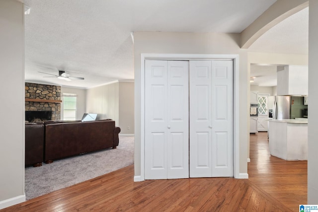 living room featuring baseboards, a ceiling fan, wood finished floors, and a fireplace