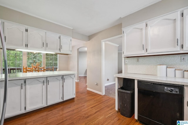kitchen featuring light countertops, arched walkways, black dishwasher, and white cabinetry