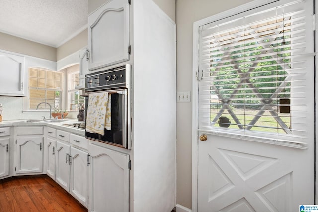 kitchen with a sink, dark wood-style floors, white cabinets, and oven