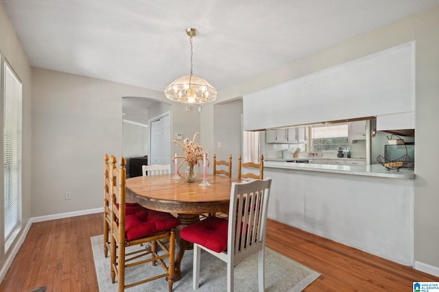 dining area featuring baseboards, arched walkways, wood finished floors, and a notable chandelier