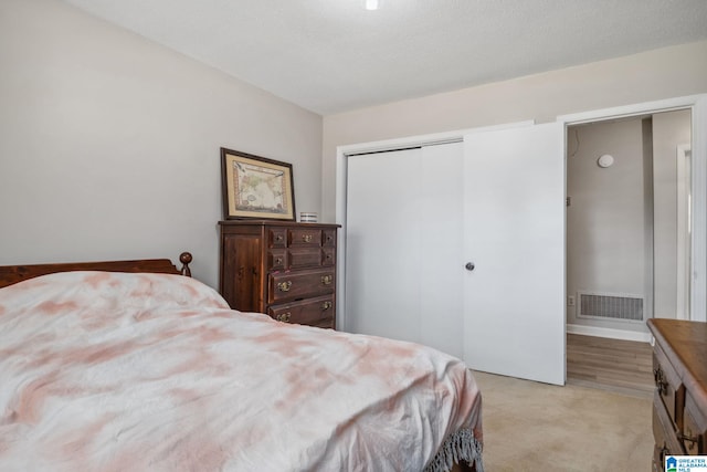 bedroom featuring a closet, light colored carpet, and visible vents