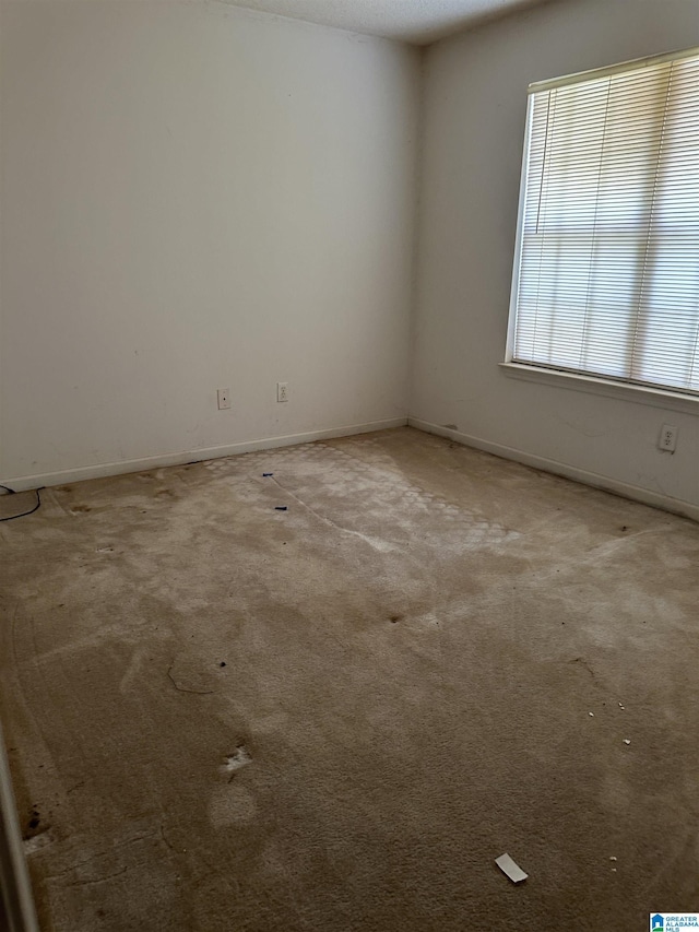 carpeted empty room featuring baseboards