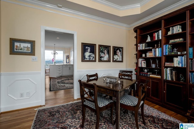 dining space with ornamental molding, a wainscoted wall, and wood finished floors