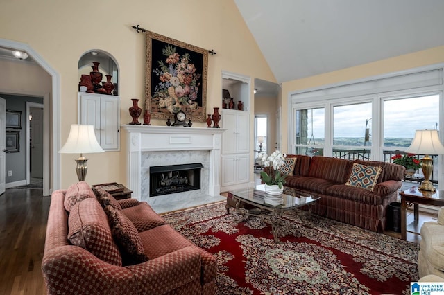 living area featuring baseboards, a high end fireplace, high vaulted ceiling, and dark wood-type flooring