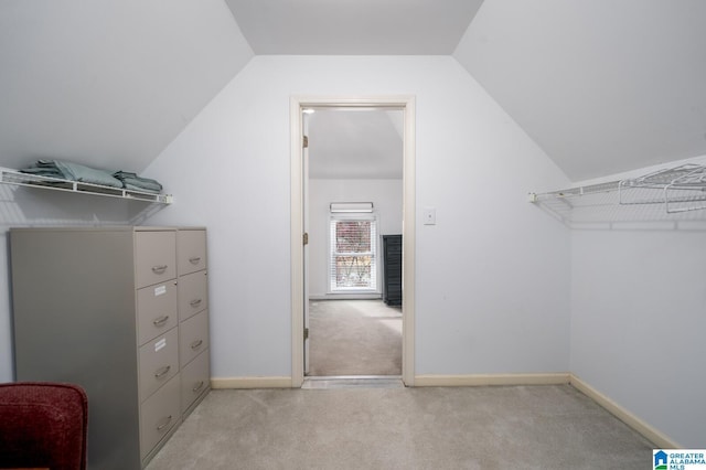 walk in closet with lofted ceiling, light colored carpet, and mail area