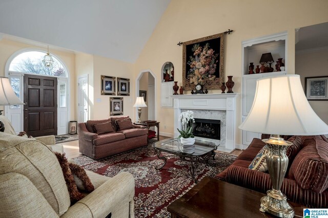 living room with a high end fireplace, high vaulted ceiling, and wood finished floors