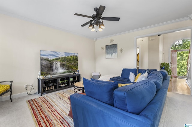 carpeted living room with crown molding, baseboards, and ceiling fan