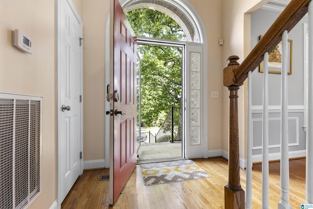 foyer entrance with baseboards, visible vents, wood finished floors, and a heating unit