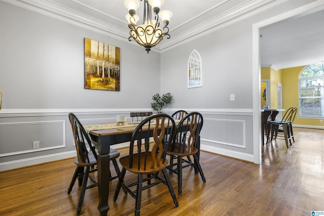 dining room featuring crown molding, an inviting chandelier, wood finished floors, and a wainscoted wall