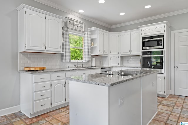 kitchen with stone tile floors, white cabinets, appliances with stainless steel finishes, and a sink