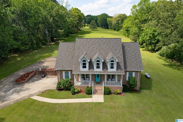 cape cod-style house with covered porch, driveway, brick siding, and a front yard