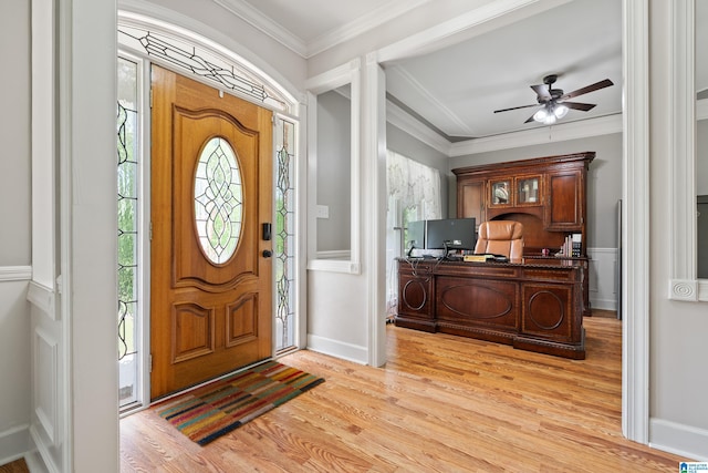 entrance foyer featuring decorative columns, a ceiling fan, crown molding, baseboards, and light wood-style flooring