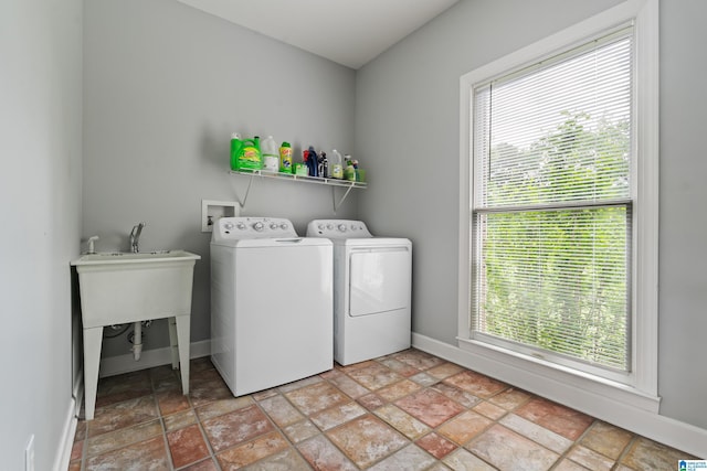 clothes washing area with washer and dryer, laundry area, stone finish flooring, and baseboards