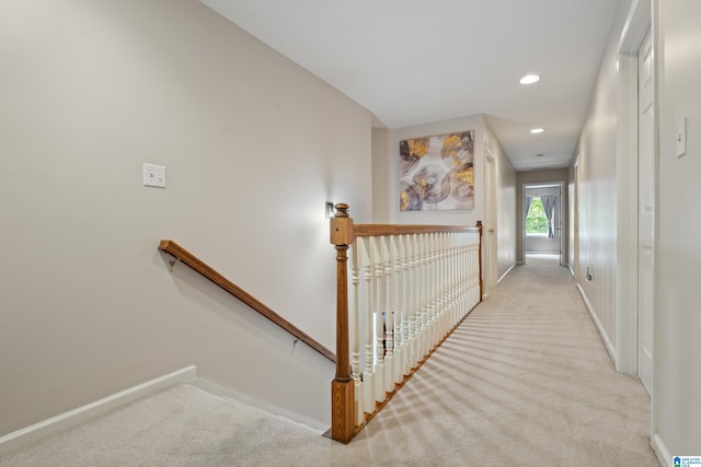 corridor with carpet floors, baseboards, and an upstairs landing