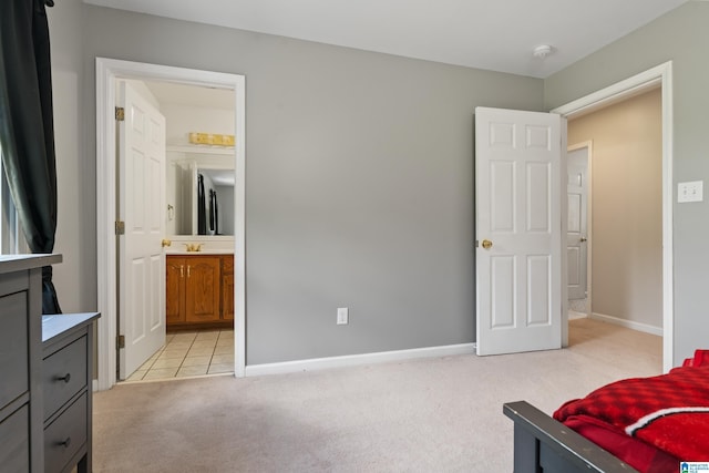 bedroom with light colored carpet, a sink, baseboards, and ensuite bathroom