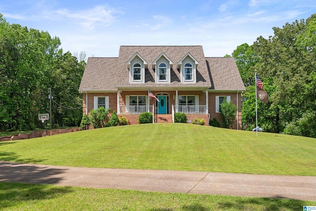 cape cod home with a porch, brick siding, and a front lawn