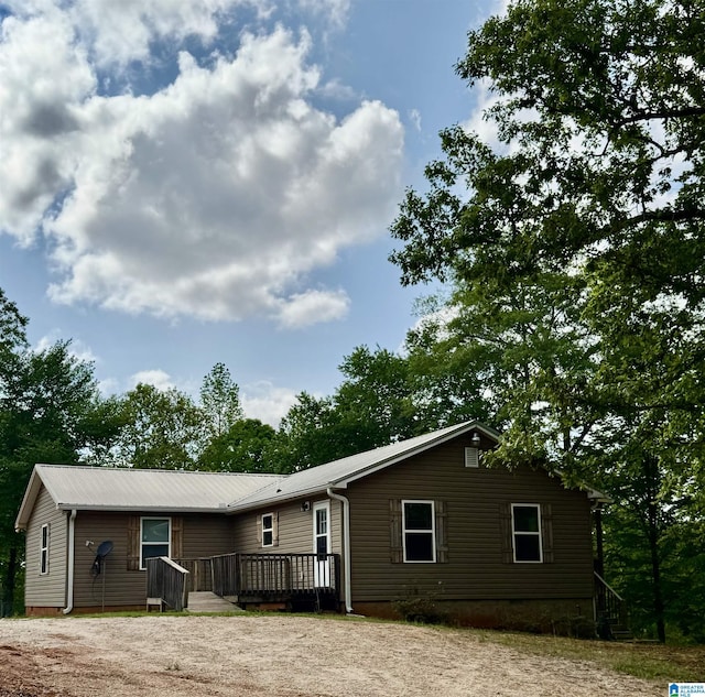 view of front of home with a wooden deck, driveway, and metal roof