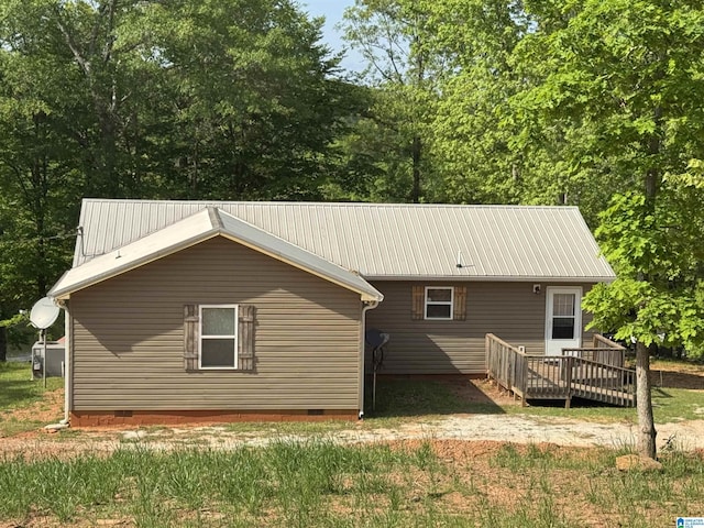 rear view of property with a wooden deck, crawl space, and metal roof