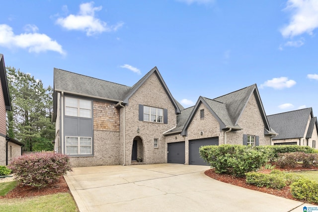 view of front facade featuring brick siding, a shingled roof, an attached garage, and driveway