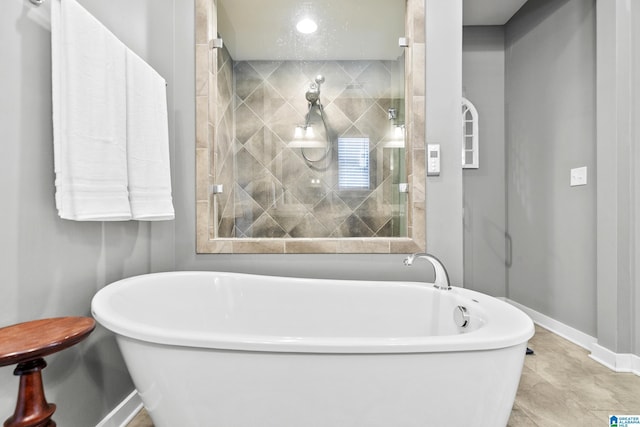 bathroom featuring a freestanding bath, baseboards, and tiled shower