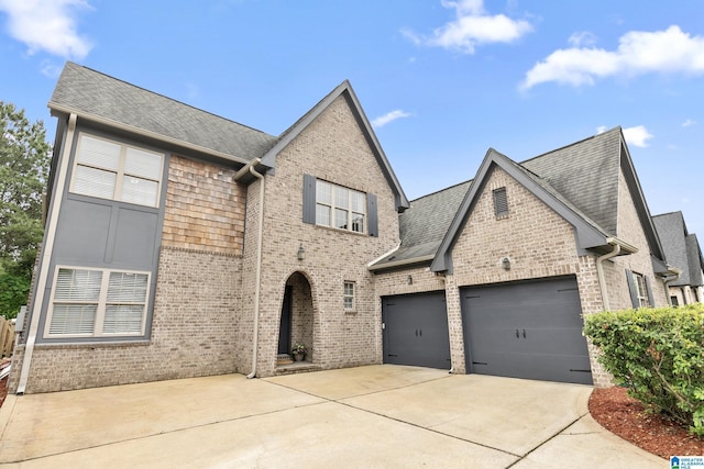 view of front of home featuring concrete driveway, brick siding, roof with shingles, and a garage