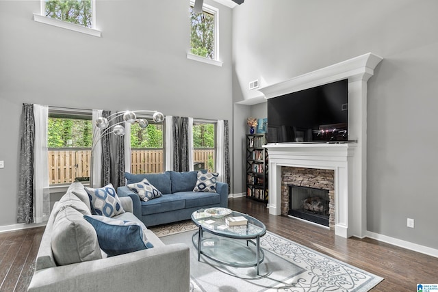 living room with a towering ceiling, wood finished floors, and a healthy amount of sunlight