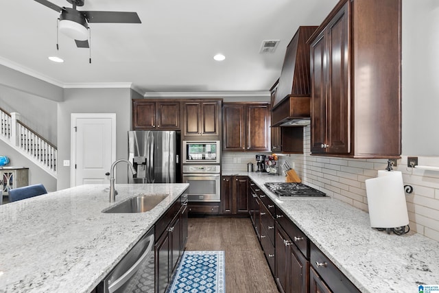 kitchen with ceiling fan, custom range hood, a sink, ornamental molding, and stainless steel appliances