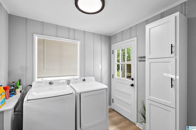 clothes washing area featuring washing machine and dryer, ornamental molding, cabinet space, and light wood-style flooring