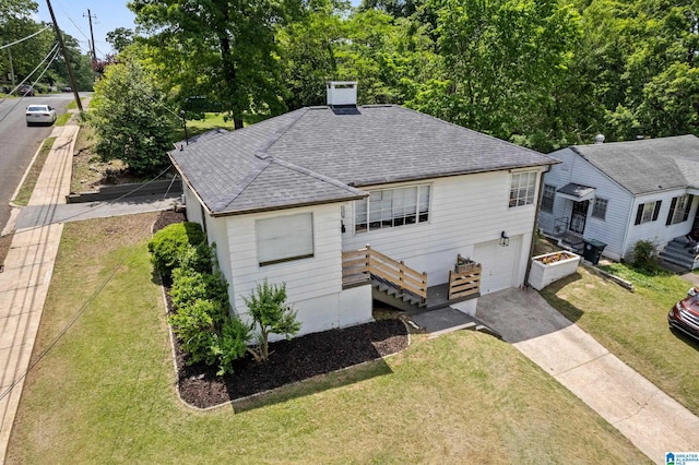 view of front of house featuring roof with shingles, driveway, an attached garage, and a front lawn