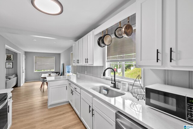 kitchen featuring black microwave, a sink, light countertops, white cabinets, and recessed lighting