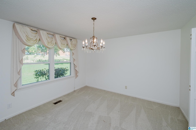 unfurnished room with carpet flooring, a notable chandelier, visible vents, and baseboards