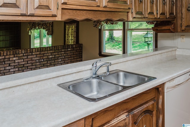 kitchen with white dishwasher, a sink, and light countertops