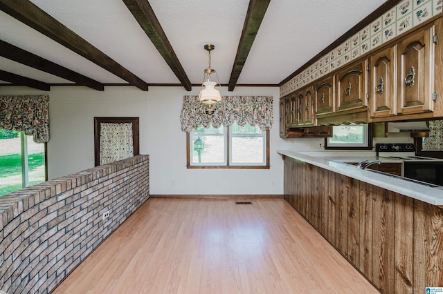 kitchen featuring beam ceiling, light wood-style floors, light countertops, range with electric cooktop, and a healthy amount of sunlight