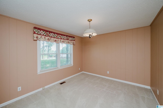 unfurnished room featuring light colored carpet, a textured ceiling, and visible vents