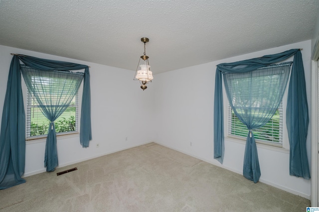 carpeted empty room featuring visible vents and a textured ceiling