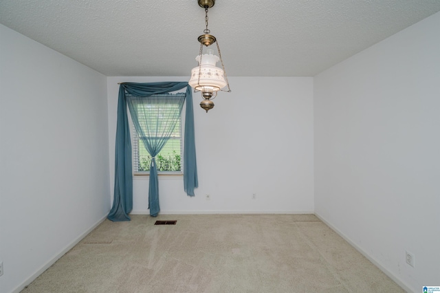 spare room featuring visible vents, a textured ceiling, carpet floors, and baseboards