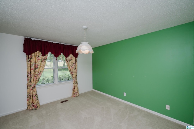 spare room with baseboards, carpet flooring, a textured ceiling, and visible vents