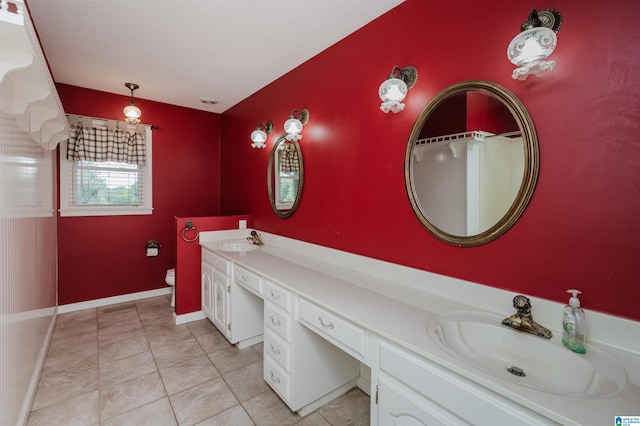 bathroom featuring double vanity, toilet, a sink, and tile patterned floors