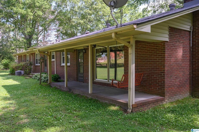 view of side of property with a yard, brick siding, and cooling unit