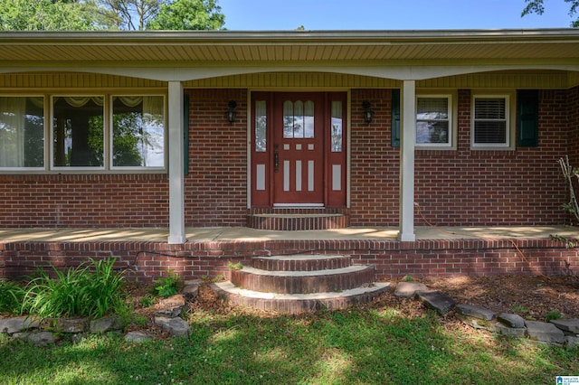property entrance featuring a porch and brick siding