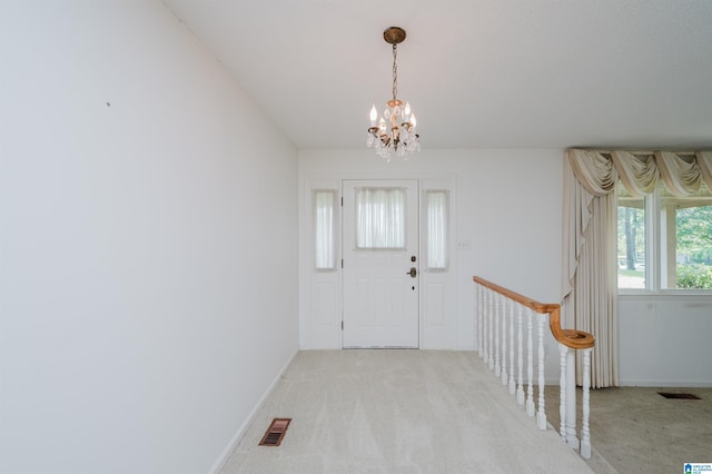 entrance foyer featuring baseboards, light colored carpet, a chandelier, and visible vents