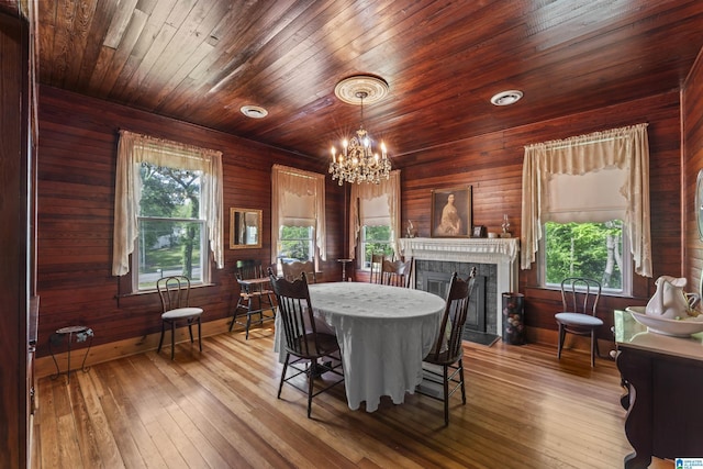 dining area featuring a fireplace, baseboards, wooden ceiling, wood-type flooring, and a chandelier
