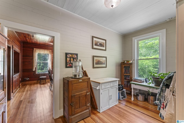 interior space with light wood-type flooring, wood walls, and wooden ceiling